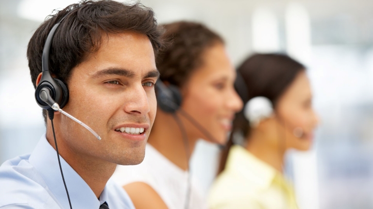 Happy employee smiles while wearing headset and discussing his performance at work | Reduce Labor Costs