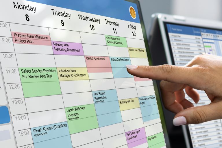 Close up of manager’s finger pointing at employee’s shift on colorful desktop calendar | Improve employee retention